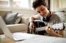 улыбающаяся девушка, играющая на гитаре дома - хобби стоковые фото и изображения